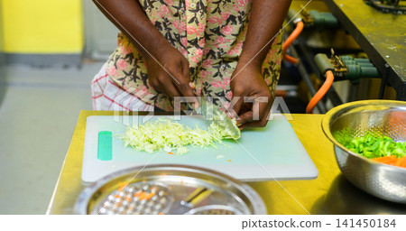 Chef slicing lettuce for a vegetable salad. Fresh ingredients being prepared in a professional kitchen 141450184