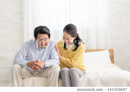 A depressed husband in bed and his supportive wife A depressed husband in bed and his supportive wife 141450697