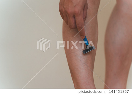 Close-up of a Japanese man in his 40s shaving his leg hair with a razor. Close-up of a Japanese man in his 40s shaving his leg hair with a razor. 141451867