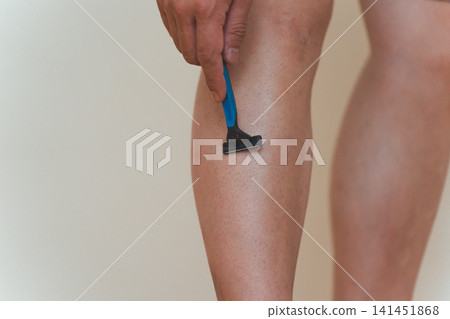 Close-up of a Japanese man in his 40s shaving his leg hair with a razor. Close-up of a Japanese man in his 40s shaving his leg hair with a razor. 141451868