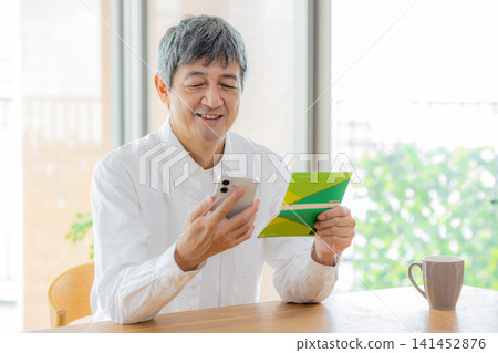 一位手持存摺和智慧型手機的老人 141452876