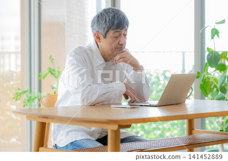 一位老人看著電腦螢幕，心事重重。 141452889