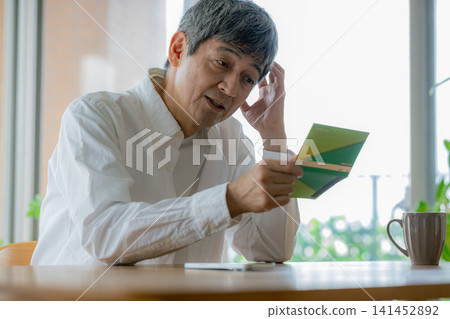 A senior man is troubled after looking at his bankbook. 141452892