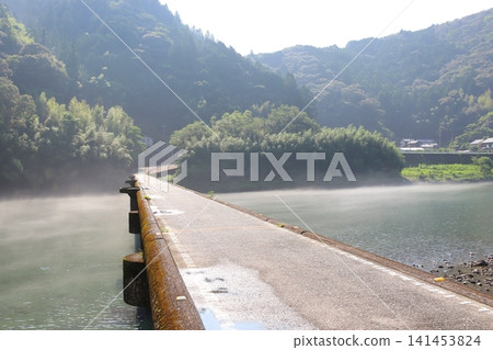 The Niyodo River, enveloped in summer morning mist, and the Nagoshiya (Nagoya) submersible bridge (Ino Town, Kochi Prefecture). The Niyodo River, enveloped in summer morning mist, and the Nagoshiya (Nagoya) submersible bridge (Ino Town, Kochi Prefecture). 141453824
