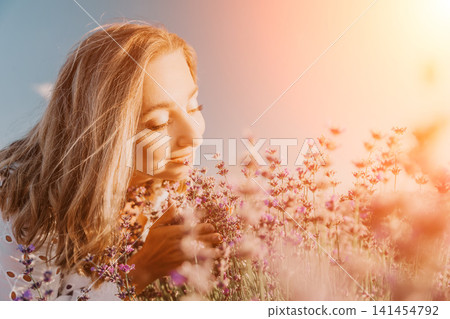 Lavender woman smelling young female enjoying the aromatic scent of purple flowers in a sunlit field during summer 141454792