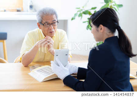 現場鑑定服務:一位老人在家中請人鑑定他的郵票和古幣。 現場鑑定服務:一位老人在家中請人鑑定他的郵票和古幣。 141454837