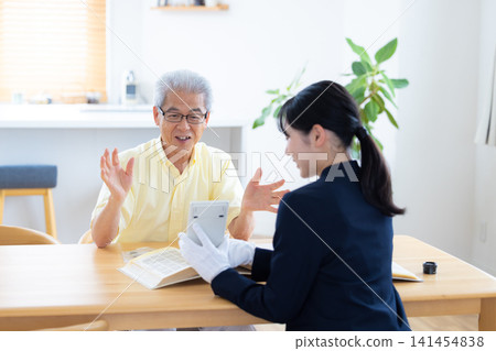 現場鑑定服務:一位老人在家中請人鑑定他的郵票和古幣。 現場鑑定服務:一位老人在家中請人鑑定他的郵票和古幣。 141454838