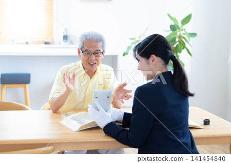 現場鑑定服務:一位老人在家中請人鑑定他的郵票和古幣。 現場鑑定服務:一位老人在家中請人鑑定他的郵票和古幣。 141454840