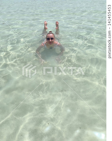 woman glides effortlessly through clear sea waters, her arms stretched wide graceful swimming pose, capturing thrill aquatic adventure, the purity ocean joy embracing an active, sun soaked lifestyle woman glides effortlessly through clear sea waters, her arms stretched wide graceful swimming pose, capturing thrill aquatic adventure, the purity ocean joy embracing an active, sun soaked lifestyle 141455453