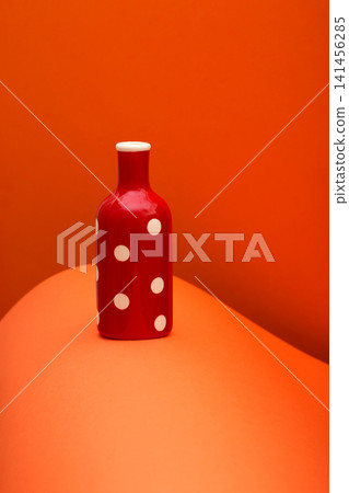 Red bottle on an abstract background of colored paper sheets Red bottle on an abstract background of colored paper sheets 141456285