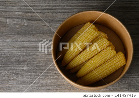 Delightful golden corn cobs arranged in a rustic bowl on a wooden tabletop Delightful golden corn cobs arranged in a rustic bowl on a wooden tabletop 141457419