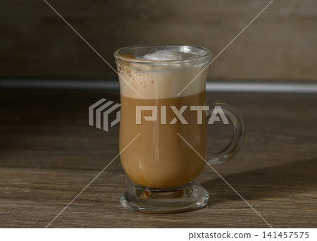 A glass mug of coffee with frothed milk A glass mug of coffee with frothed milk 141457575