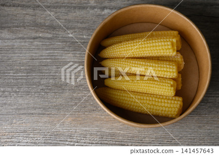 Freshly harvested baby corn in a rustic bowl resting on a weathered wooden table Freshly harvested baby corn in a rustic bowl resting on a weathered wooden table 141457643