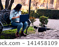 A beautiful Latina executive working remotely from home, in her backyard, with her laptop, next to her cat, touching it, joy, affection. Teleworking, marketing. 141458109