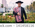 Portrait of a smiling, cheerful young man dressed as a Chilean huaso, celebrating and posing to dance cueca, a traditional Chilean dance. Chilean traditions, celebration, and culture. 141458116
