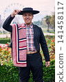 Portrait of a smiling, cheerful young man dressed as a Chilean huaso, celebrating and posing to dance cueca, a traditional Chilean dance. Chilean traditions, celebration, and culture. 141458117
