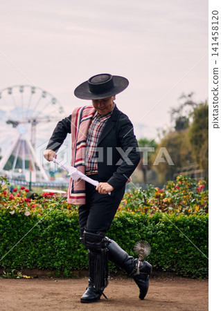 Portrait of a smiling, cheerful young man dressed as a Chilean huaso, celebrating and posing to dance cueca, a traditional Chilean dance. Chilean traditions, celebration, and culture. Portrait of a smiling, cheerful young man dressed as a Chilean huaso, celebrating and posing to dance cueca, a traditional Chilean dance. Chilean traditions, celebration, and culture. 141458120
