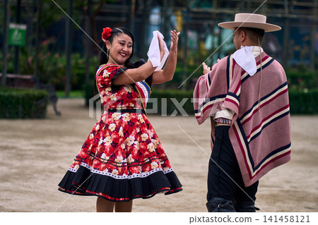 A pair of young Chilean Latin dancers dancing cuecas, the Chilean national dance, in a very cheerful, charismatic, and romantic manner. Chilean Independence Day A pair of young Chilean Latin dancers dancing cuecas, the Chilean national dance, in a very cheerful, charismatic, and romantic manner. Chilean Independence Day 141458121