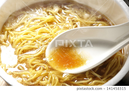 Scoop the soup from the cup noodles with a spoon. Scoop the soup from the cup noodles with a spoon. 141458315