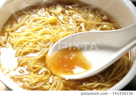 Scoop the soup from the cup noodles with a spoon. Scoop the soup from the cup noodles with a spoon. 141458316
