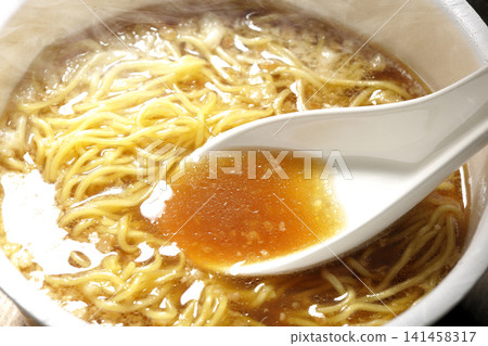 用湯匙將杯麵裡的湯舀出來。 用湯匙將杯麵裡的湯舀出來。 141458317