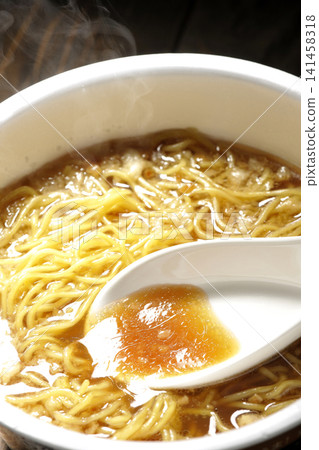 Scoop the soup from the cup noodles with a spoon. Scoop the soup from the cup noodles with a spoon. 141458318
