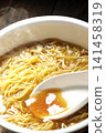 Scoop the soup from the cup noodles with a spoon. 141458319