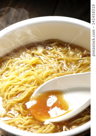 Scoop the soup from the cup noodles with a spoon. Scoop the soup from the cup noodles with a spoon. 141458319