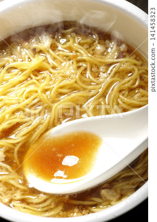 用湯匙將杯麵裡的湯舀出來。 141458323
