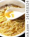Scoop the soup from the cup noodles with a spoon. 141458324