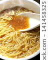 Scoop the soup from the cup noodles with a spoon. 141458325