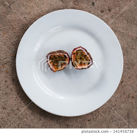 Passion Fruit Cut in Half on White Plate, Top View Passion Fruit Cut in Half on White Plate, Top View 141458738