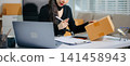 Asian e-commerce entrepreneur live streaming with laptop and parcel boxes. Online seller, content creator, social media marketing, remote business 141458943