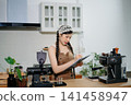 Focused Asian female barista taking stock and managing inventory with a clipboard at a modern cafe counter. 141458947