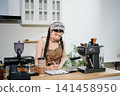 Focused Asian female barista taking stock and managing inventory with a clipboard at a modern cafe counter. 141458950