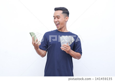 Man smiles joyfully while holding cash and phone. He appears delighted, possibly celebrating earnings or success. Pure white background ensures focus on his expression and objects Man smiles joyfully while holding cash and phone. He appears delighted, possibly celebrating earnings or success. Pure white background ensures focus on his expression and objects 141459135