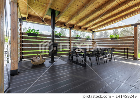 Wide View of Covered Wooden Terrace with Stove and Dining Area 141459249