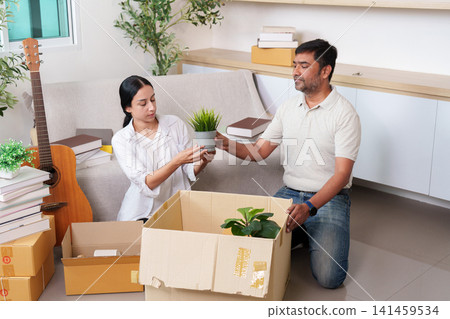 South Asian couple packing cardboard boxes with plants for home relocation South Asian couple packing cardboard boxes with plants for home relocation 141459534