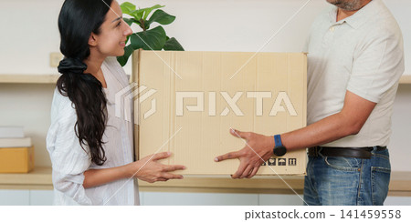 Indian couple carrying cardboard box together while moving into new home Indian couple carrying cardboard box together while moving into new home 141459558