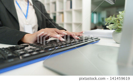 Cropped hands of businesswoman typing on keyboard at office desk for business administration 141459619