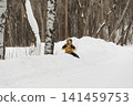 A child in a yellow jacket and gray hat plays in a winter park. A snowy winter forest, a fairy tale. An active, healthy lifestyle and fun games in the snow during the holidays 141459753