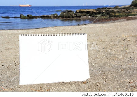 A blank sketchbook placed on the sandy beach. A blank sketchbook placed on the sandy beach. 141460116