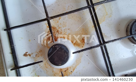 Close up of a dirty white gas stovetop with heavy brown and orange grease stains around a single burner and metal grate... Close up of a dirty white gas stovetop with heavy brown and orange grease stains around a single burner and metal grate... 141460230