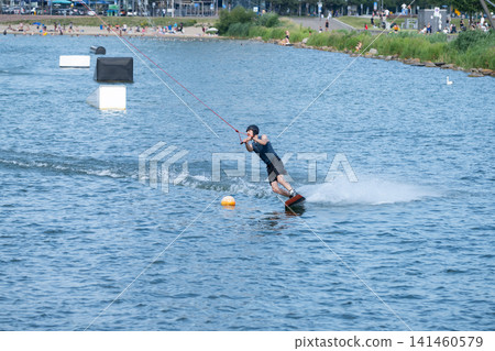 Cable Wakeboarder Riding on Lake in Summer Cable Wakeboarder Riding on Lake in Summer 141460579