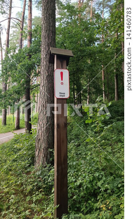Warning sign on wooden post in forest with steep slope notice Warning sign on wooden post in forest with steep slope notice 141460783