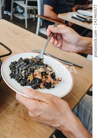 at a restaurant, a man serves himself arros negre at a restaurant, a man serves himself arros negre 141460877