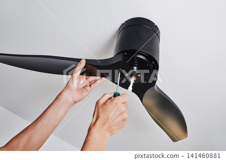 man installing a black three blade ceiling fan man installing a black three blade ceiling fan 141460881