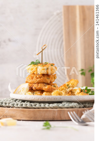 Delicious golden crispy cod fish fritters stacked on a rustic plate with fresh green parsley garnish and a lemon wedge for a perfect appetizer Delicious golden crispy cod fish fritters stacked on a rustic plate with fresh green parsley garnish and a lemon wedge for a perfect appetizer 141461366