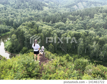 A woman with a dog came to the top and watch the panorama landscape valley. River, forest, years, gorge adventure A woman with a dog came to the top and watch the panorama landscape valley. River, forest, years, gorge adventure 141461722