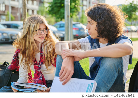 Two teenage students talking outdoors while studying together in city park Two teenage students talking outdoors while studying together in city park 141462641